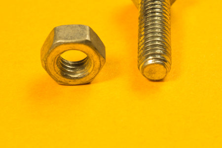 Steel screw on a yellow background. working tools