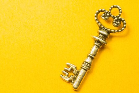Old key isolated on yellow background. safety and security conceptの写真素材