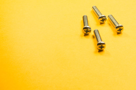 Steel screw on a yellow background. working tools