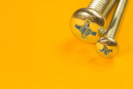Steel screw on a yellow background. working toolsの写真素材