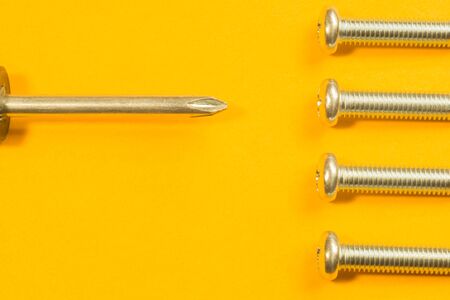 Steel screw on a yellow background. working toolsの写真素材