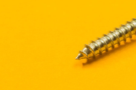 Steel screw on a yellow background. working tools