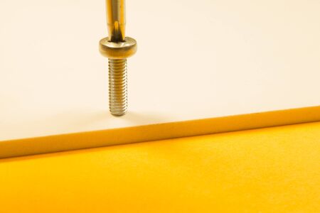 Steel screw on a yellow background. working toolsの写真素材