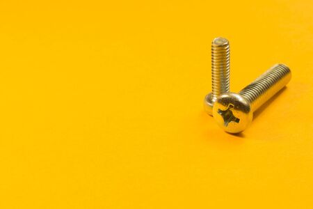 Steel screw on a yellow background. working toolsの写真素材