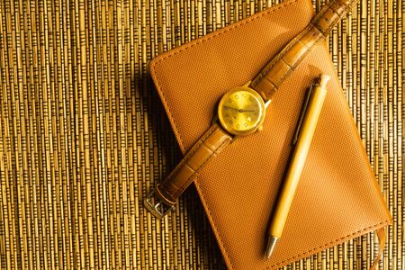 Diary and pen with wristwatch on a wooden bamboo background. notebook and pen top view. copy spaceの写真素材