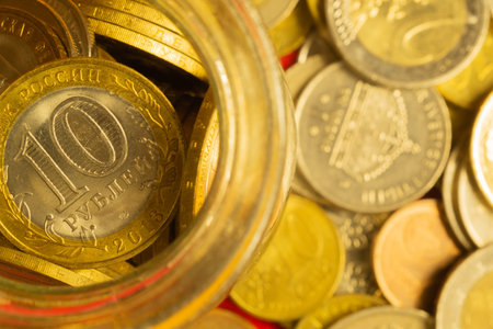 Coins of different countries in a glass jar. a lot of metal coins of different denominations and...