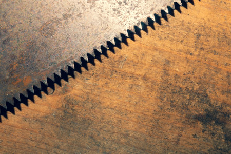 Old hand saw on a dirty wooden background. working area with hand tool. carpentry instrument. manual...