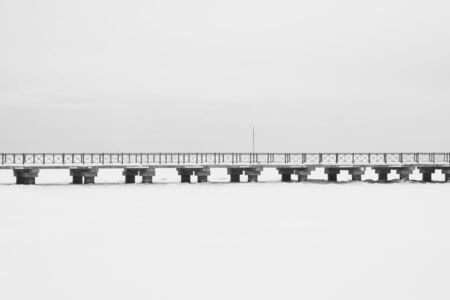 Bridge on the frozen lake. long footbridge dividing the horizon. conceptual minimalistic image. black and white background with copy spaceの写真素材