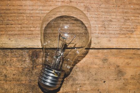 Light bulb on a wooden background. old lamp lies on the table.の写真素材