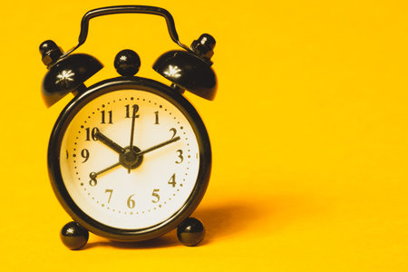 Classic alarm clock on yellow background. vintage watch with round dial. copy space