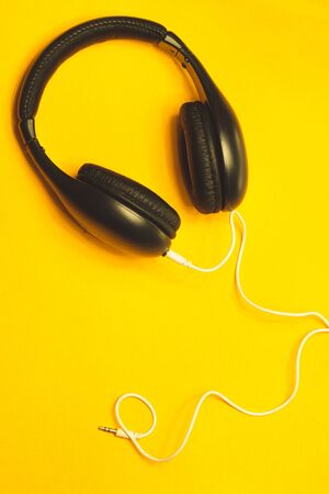 Black headphones with white cable on a yellow background. modern earphonesの写真素材