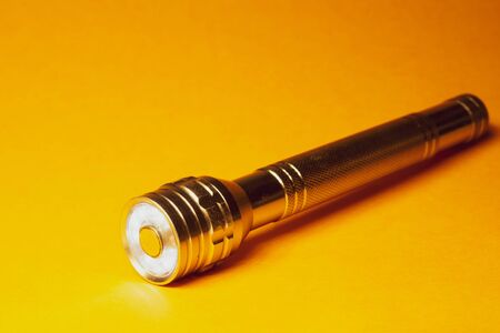 Metal flashlight on a yellow backgroundの写真素材