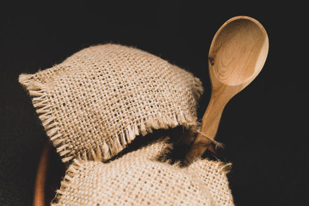 Honey pots with linen cloth with wooden spoon on dark background