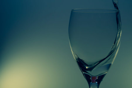 Water pouring into glass. water splash in glass on glowing background. liquid splashing in wine...