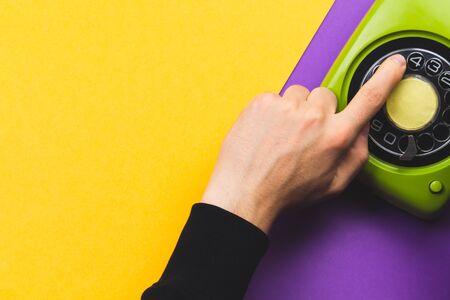 Hand dialing a number on a classic phone with round dial. vintage green telephone. copy spaceの写真素材