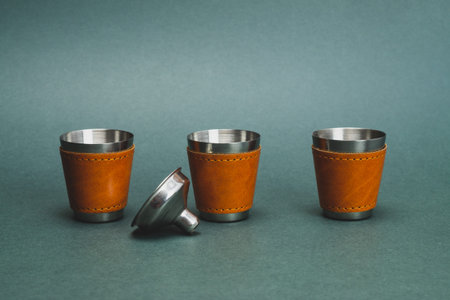 Metallic shot glasses in a row. steel funnel. travel shot glass for alcohol with leather casing over the stainless steel. personal accessory set. copy spaceの写真素材