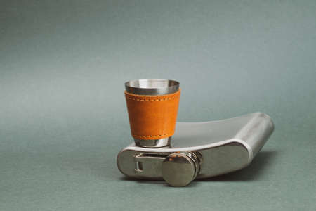 Stainless steel flask with shot glass. travel shot glass for alcohol with leather casing over the metal. personal accessory set. copy spaceの写真素材