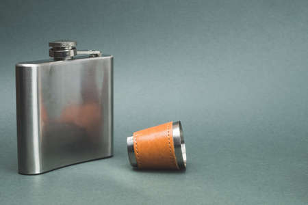 Stainless steel flask with shot glass. travel shot glass for alcohol with leather casing over the metal. personal accessory set. copy spaceの写真素材