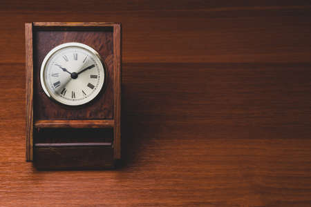 Retro wooden clock. square shaped vintage clock with round dial. wood table. copy spaceの写真素材