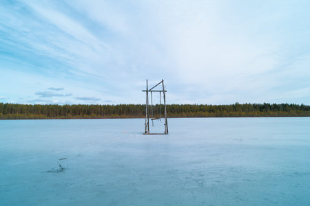 Wooden swing on a frozen lake. solitude concept. swing stand in the middle of frosted pond. nature...