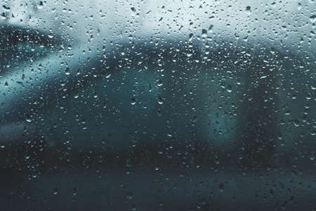 Raindrops on glass. view through the car window. heavy rain. abstract background with droplets on transparent surfaceの写真素材