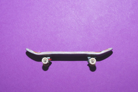 Small skateboard on purple background. tiny skate for fingers. fingerboard close up. copy space