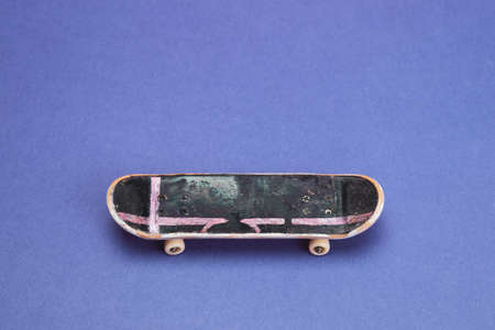 Small skateboard on blue background. tiny skate for fingers. fingerboard close up. copy spaceの写真素材
