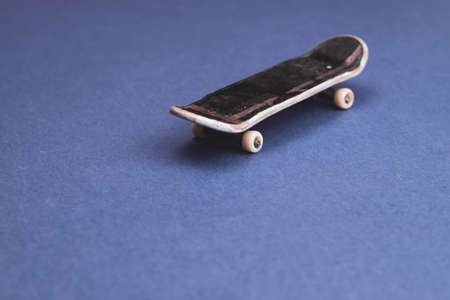 Small skateboard on blue background. tiny skate for fingers. fingerboard close up. copy spaceの写真素材