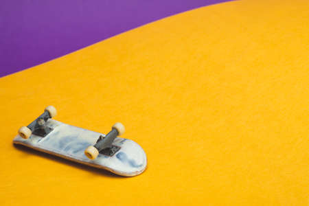 Small skateboard on color background. tiny skate for fingers. fingerboard close up. home leisure concept. copy spaceの写真素材