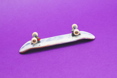 Small skateboard on purple background. tiny skate for fingers. fingerboard close up. copy spaceの写真素材