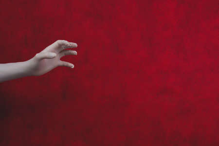 Hand in protective glove on a red background. gesturing hand in white medical gloveの写真素材