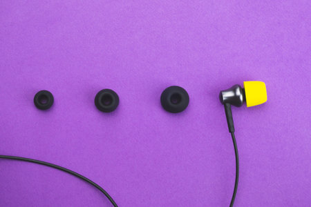 Individuality concept. earphone with yellow ear pad in the end of row of gray embouchures. in-ear...