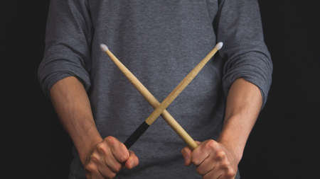 Hands holds crossed wooden drumsticks in the darkの写真素材