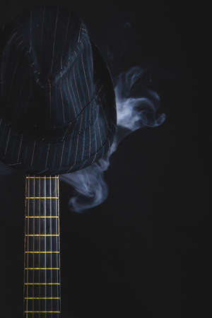 Smoking hat hangs on the guitar fretboard. acoustic musical instrument. strings on the guitar neck close upの写真素材