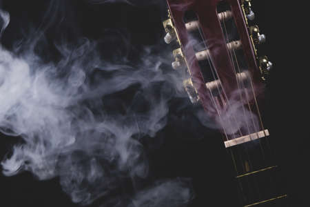 Guitar in smoke on the black background. acoustic musical instrument. strings on the guitar neckの写真素材