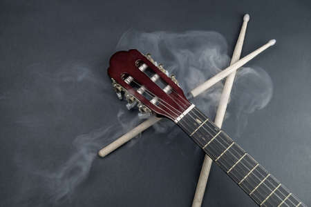 Drumsticks and guitar fretboard in smoke. acoustic musical instrument. copy spaceの写真素材