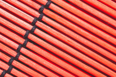 Bamboo mat background close up. wooden backdrop. red wooden sticks bound togetherの写真素材