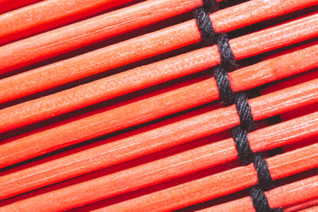 Bamboo mat background close up. wooden backdrop. red wooden sticks bound togetherの写真素材