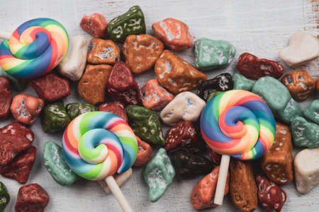 Festive decoration. lollipops and candy pebbles. sweets in the form of colored stones. white woooden background with colorful candiesの写真素材