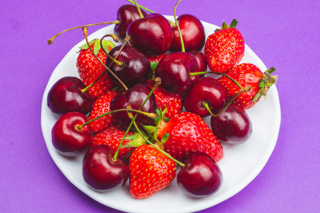 Strawberries and cherries on the white plate