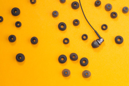 Earphones between of ear cushions on yellow background. in-ear headphones with many embouchures....