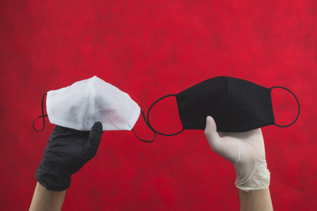 White protective mask in hand with black glove. black protective mask in hand with white glove....