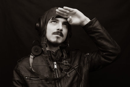 Male portrait in retro style. young man in the vintage aviation suit on the black background