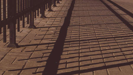 Shadow of the iron fencing on the pavement. summer day. abstract backgroundの写真素材