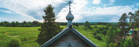 Old wooden church on the pasture field. rural panoramic landscape. roof of ancient chapel. traditional architectureの写真素材