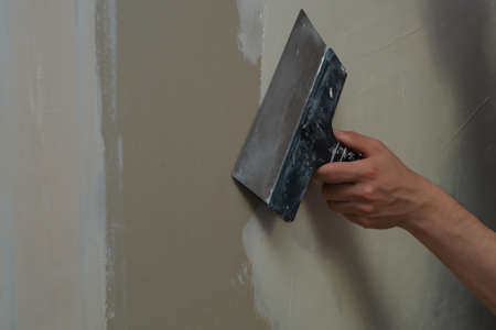Hand holds construction spatula with putty. trowel with spackling. process of renovationの写真素材