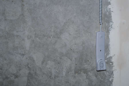 Intercom phone receiver on gray concrete background. handset hanging on the wire close upの写真素材
