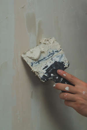 Hand holds construction spatula with putty. trowel with spackling. process of renovationの写真素材