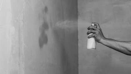 Spray can in the hand. spraying paint on the wall. painting processの写真素材