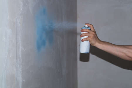 Spray can in the hand. spraying paint on the wall. painting processの写真素材